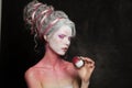 Magician woman with creative body art holding res snowy apple portrait. Carnival or Halloween makeup