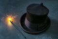 magicians hat lying on its side, wand with a glowing tip nearby