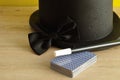 A magicians hat, wand, bow tie and a deck of cards