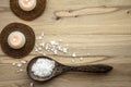 Magnesium Chloride Flakes scattered around brown wooden spoon on natural wood background.