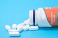 Magnesium citrate pills spill out of a jar on a blue background.