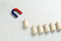 Magnet attracting human figure among other ones on white table Royalty Free Stock Photo