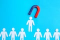 Magnet attracting paper cutouts of humans on light blue background, flat lay Royalty Free Stock Photo