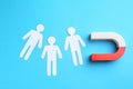 Magnet attracting paper cutouts of humans on light blue background, flat lay Royalty Free Stock Photo