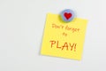 Magnet and yellow sticky note reminder to play on refrigerator Royalty Free Stock Photo