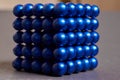 Magnetic cube made of blue metal balls on a colored background