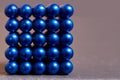 Magnetic cube made of blue metal balls on a colored background