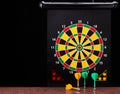 Magnetic dart arrows on granite surface and dart board background. Royalty Free Stock Photo