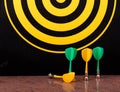 Magnetic dart arrows on granite surface and dart board background. Royalty Free Stock Photo