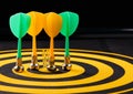 Magnetic dart arrows on yellow dart board. black background Royalty Free Stock Photo