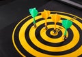 Magnetic dart arrows on yellow dart board. black background Royalty Free Stock Photo