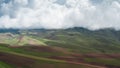 A magnificent aerial landscape with green hills and brown plowed lands under huge white swirling moving clouds. A Royalty Free Stock Photo