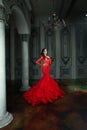Magnificent brunette fashion model woman wearing fashionable red evening gown posing in vintage palace interior