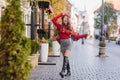 Magnificent caucasian girl in leather black shoes standing with legs crossed on pavement. Outdoor portrait of french