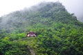 Magnificent Chinese temple on a steep rock surrounded by green tropical forest. Misty weather, fog. Taiwanese landscape, travel