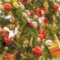 Magnificent Christmas tree decorated with silver and red balls and packages wrapped in wrapping paper, close-up view