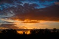 Magnificent evening sky with orange clouds at sunset behind silhouettes of bare trees. Deep horizon. Royalty Free Stock Photo