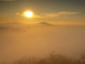 Magnificent heavy mist in landscape. Autumn fogy sunrise in a countryside. Hill increased from fog, the fog is colored to orange Royalty Free Stock Photo