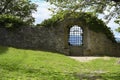 Magnificent lattice window in the fortress stone wall overlooking the mountains, with a green lawn nearby Royalty Free Stock Photo