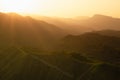 Magnificent mountain landscape - panorama view on lush green ridges, folded hills, terraces in silhouette in golden orange sunset