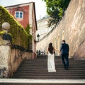 The magnificent newlyweds are going up the old baroque stairs. Prague location. The close-up back view.