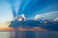 Magnificent sunset over sea. Sun covered by picturesque cloud with beautiful shine sun beams in sky Royalty Free Stock Photo