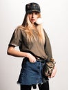 Magnificent white girl in military clothes posing with flask. Studio portrait of beautiful lady in jeans skirt looking