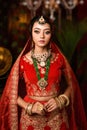 Magnificent young Indian bride in luxurious bridal costume with makeup and heavy jewellery with classic vintage interior in studio Royalty Free Stock Photo