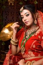 Magnificent young Indian bride in luxurious dress and precious jewellery is sitting in a chair in a luxury apartment. Classic Royalty Free Stock Photo