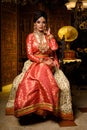 Magnificent young Indian bride in luxurious dress and precious jewellery is sitting in a chair in a luxury apartment. Classic Royalty Free Stock Photo