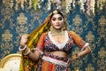 Magnificent young Indian bride in luxurious dress and precious jewellery is standing in a banquet hall. Wedding lifestyle fashion