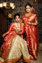 Magnificent young Indian brides in luxurious bridal costume with makeup and heavy jewellery with classic vintage interior in