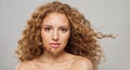 Magnificient wavy hair woman. Young fashion model with long curly hairstyle and natural fresh clear skin posing on white Royalty Free Stock Photo