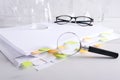 Magnifier against stack of documents, medical glassware, glasses on the white laboratory desk