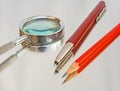 Magnifier, biro and pencil. Royalty Free Stock Photo