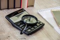 Magnifier on a calculator, smartphone, notepad and books. Close-up. Royalty Free Stock Photo