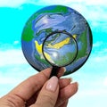 Magnifier in a female hand, enlarging the globe. Royalty Free Stock Photo