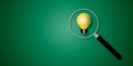 Magnifier focuses on the yellow light bulb on green background. Ideas inspiration concepts of business finance or goal to success. Royalty Free Stock Photo