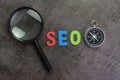 Magnifier glass, colorful alphabet SEO and compass on dark chalk
