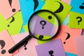 Magnifier glass on different colorful paper cards with question marks, top view Royalty Free Stock Photo