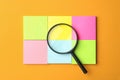 Magnifier glass and different memory stickers on orange background. Find keywords concept