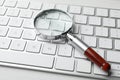 Magnifier glass and keyboard on white table. Find keywords concept Royalty Free Stock Photo