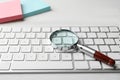 Magnifier glass and keyboard on white table. Find keywords concept Royalty Free Stock Photo