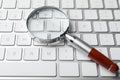 Magnifier glass on keyboard, closeup. Find keywords concept Royalty Free Stock Photo