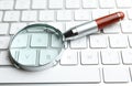 Magnifier glass on modern keyboard. Find keywords concept Royalty Free Stock Photo