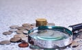 Magnifier glass with pile of coins,concept photo. Royalty Free Stock Photo