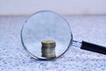 Magnifier glass with single stack of coins,concept photo. Royalty Free Stock Photo