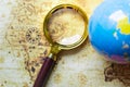 Magnifier and globe on old map background. Royalty Free Stock Photo
