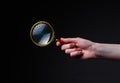 Magnifier or loupe in woman hand on black background. Concept of searching and studying