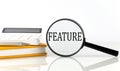 Magnifier with text FEATURE with notebook, calculator on the white background